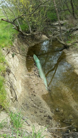Exposed water infrastructure is visible within this incised section of stream.