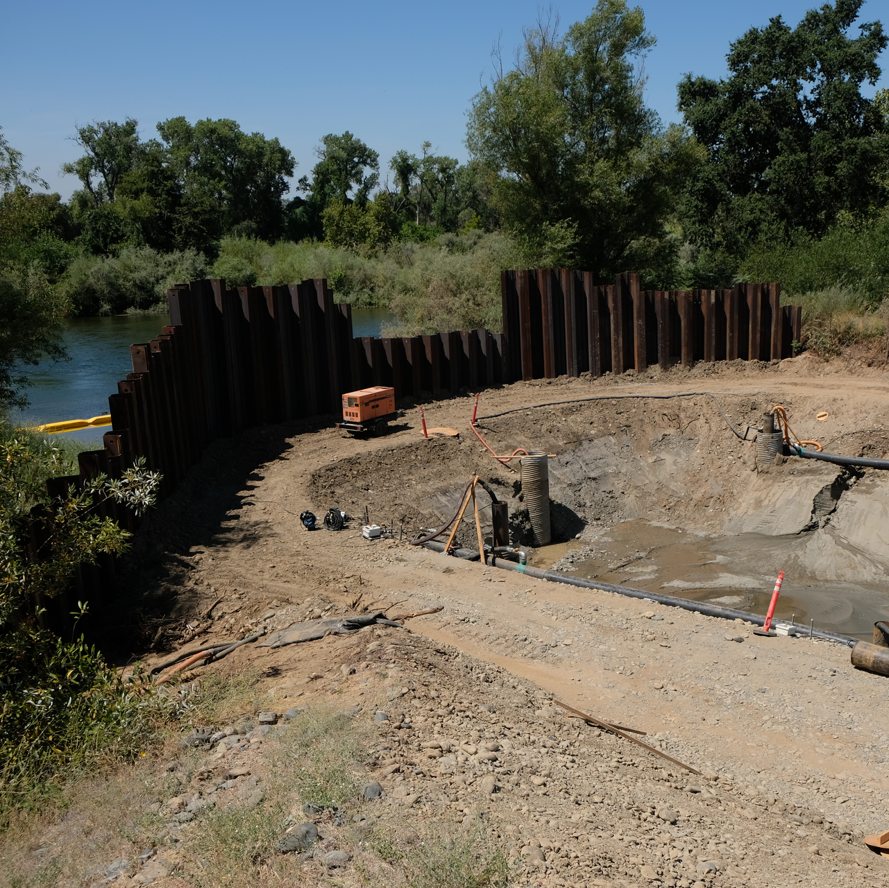 The system comprises eight dewatering pumps in narrow well casings at either side of the trench.