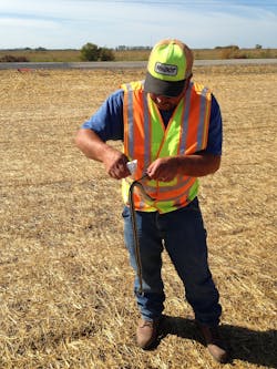 Minnesota DOT Inspector Delmar Peterson removes a snake from plastic erosion control netting. Some 60 snakes total were cut loose.