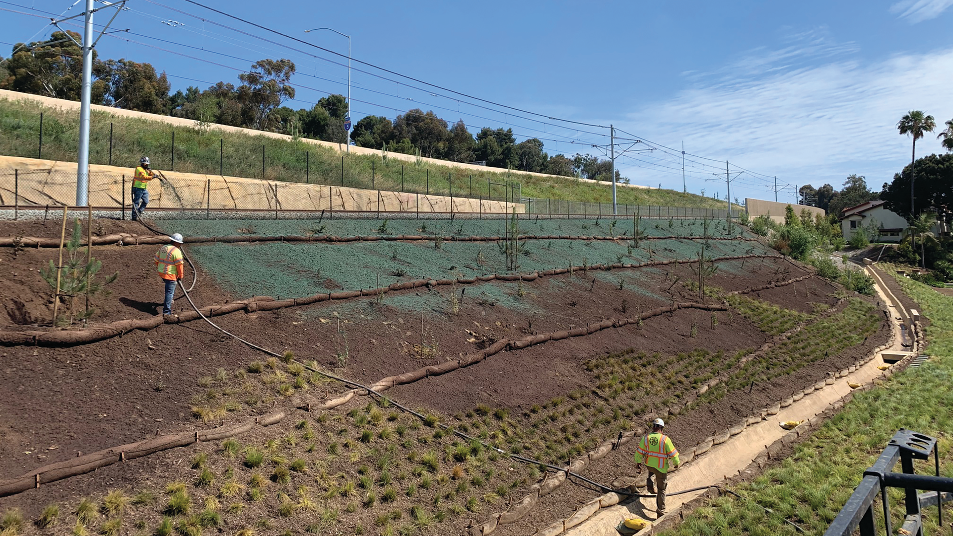 Workers applying the hydraulic erosion control product to the slopes along the railway.