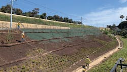 Workers applying the hydraulic erosion control product to the slopes along the railway. Workers applying the hydraulic erosion control product to the slopes along the railway.