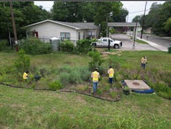 Crew maintaining rain garden next to Community Enhancement food garden with cistern. Crew maintaining rain garden next to Community Enhancement food garden with cistern.