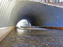 A large corrugated steel culvert in an arch shape.