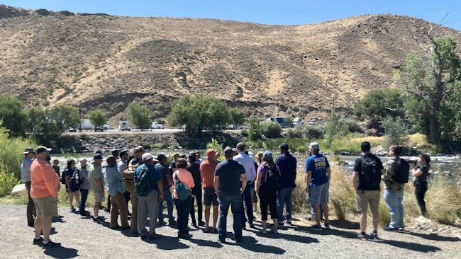 A group gathers around Danielle Henderson as she talks about Truckee River.