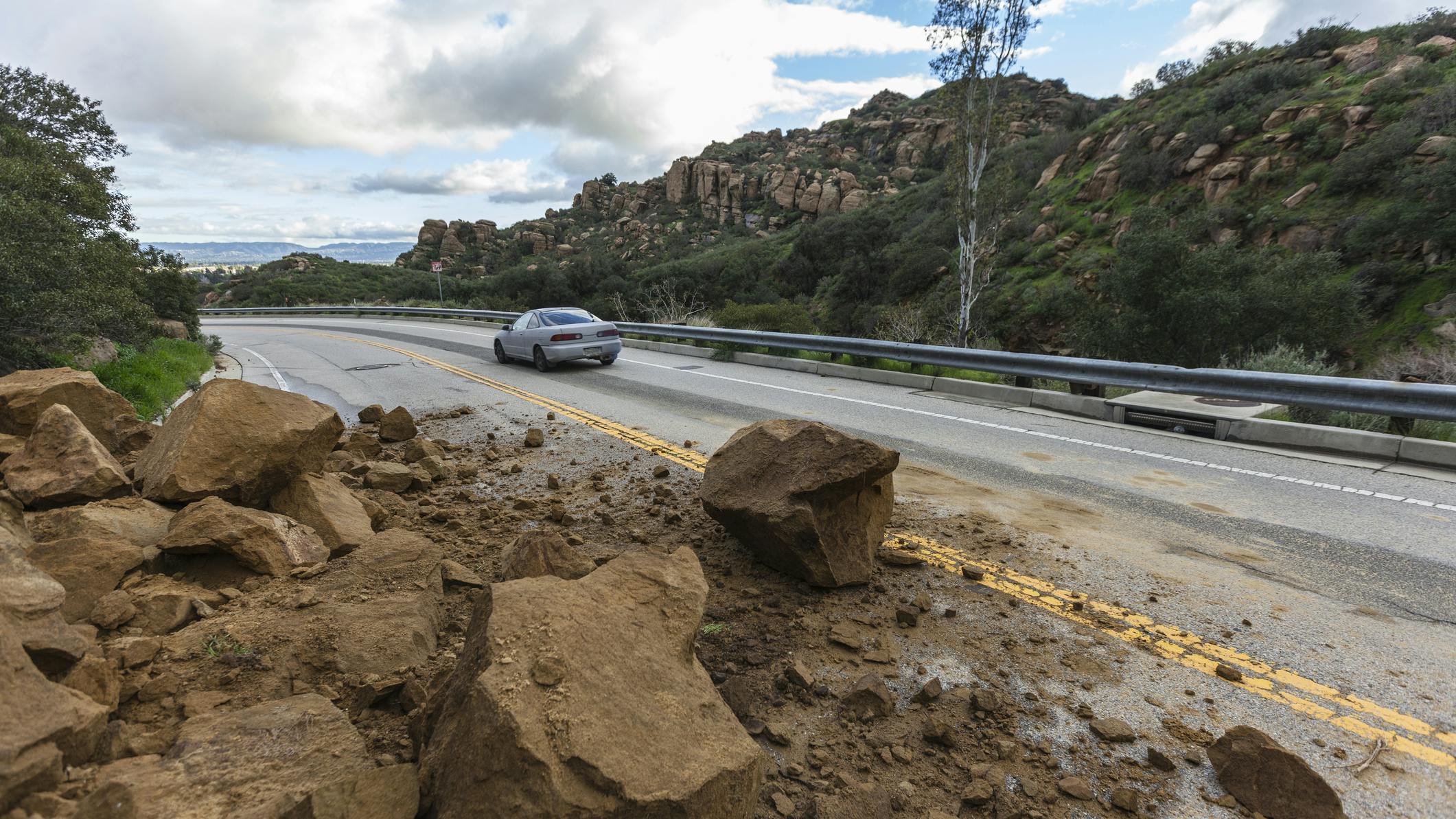 Rockslide Roadway Los Angeles. Los Angeles, California, USA - February 18, 2017: Car passing storm caused rock slide on Santa Susana Pass Road in the San Fernando Valley.