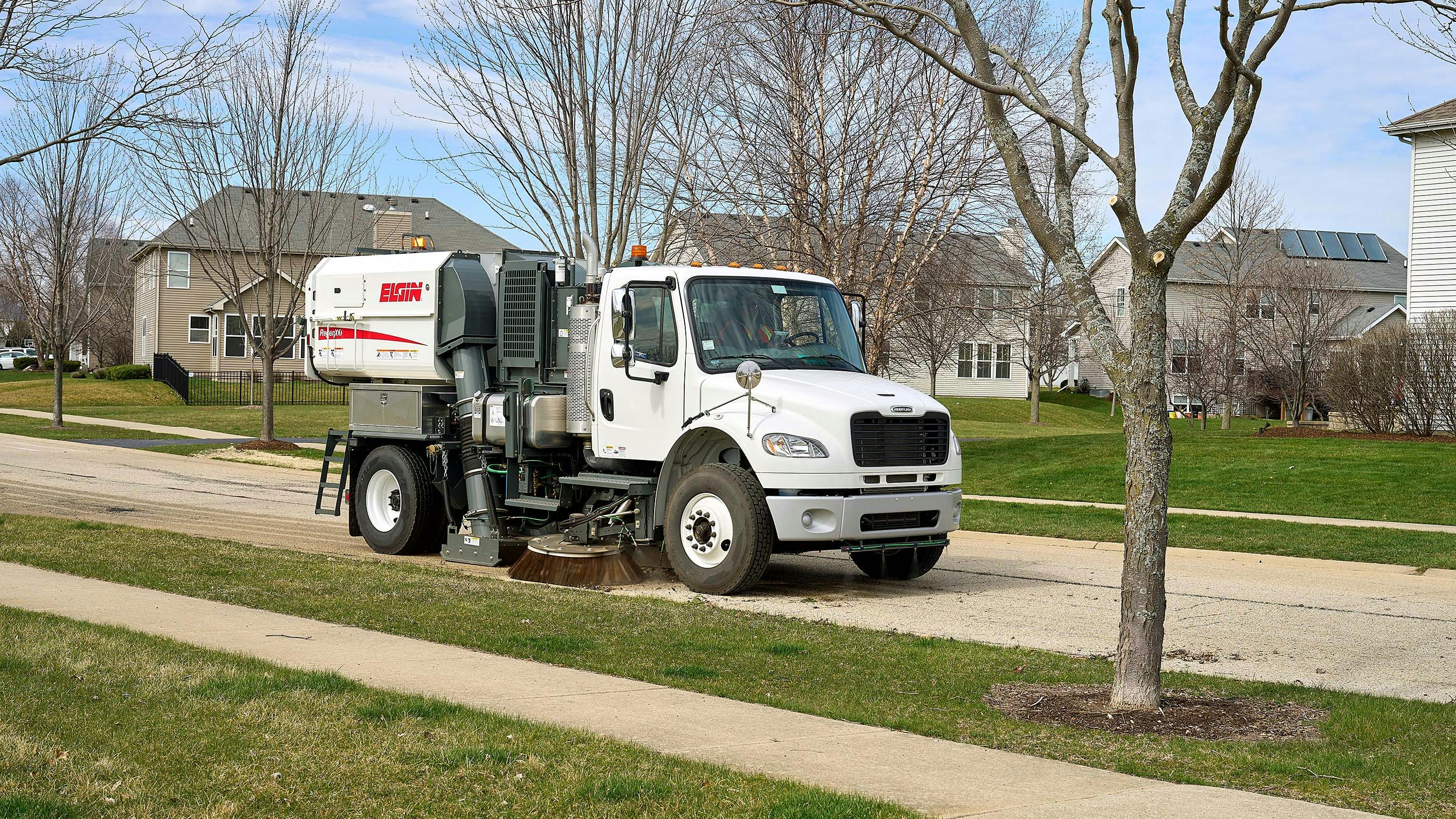 Elgin RegenX1 sweeping a street in a residential neighborhood.