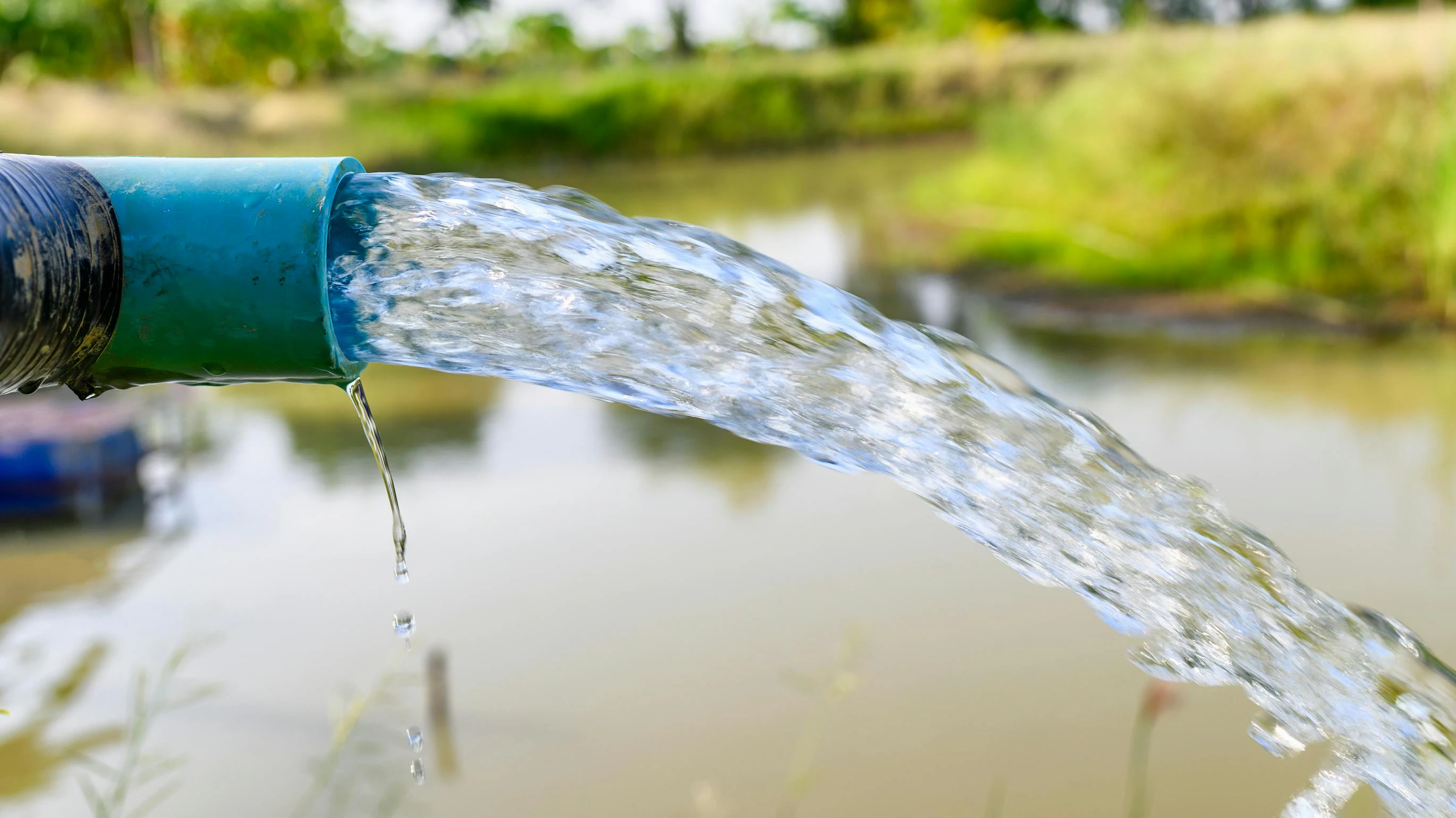 Agriculture blue pipe with groundwater gushing in pond