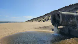 An outflow pipe discharges water onto a sunny beach, punctuating the connection between drainage infrastructure and coastal ecosystems. An outflow pipe discharges water onto a sunny beach, punctuating the connection between drainage infrastructure and coastal ecosystems.
