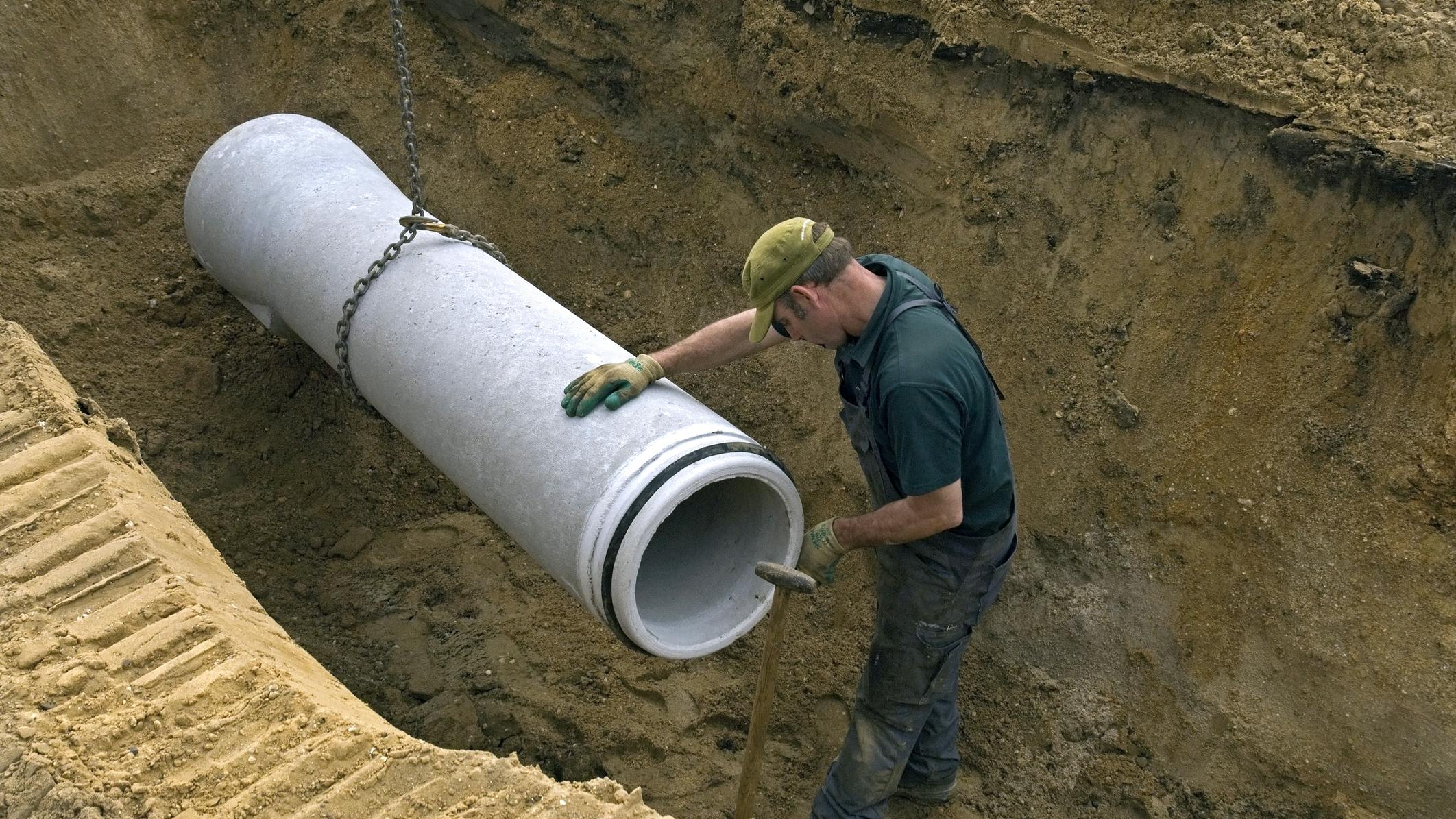 Worker laying new sewer pipe in slot in the street