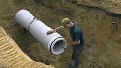 Worker laying new sewer pipe in slot in the street Worker laying new sewer pipe in slot in the street
