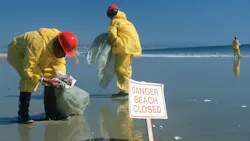 Hazardous material workers cleaning up oil spill, Huntington Beach, CA Hazardous material workers cleaning up oil spill, Huntington Beach, CA