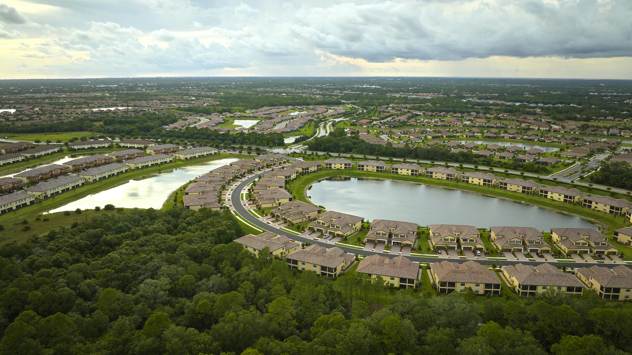 Aerial view of tightly located family houses with retention ponds to prevent flooding in Florida closed suburban area.