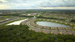Aerial view of tightly located family houses with retention ponds to prevent flooding in Florida closed suburban area.